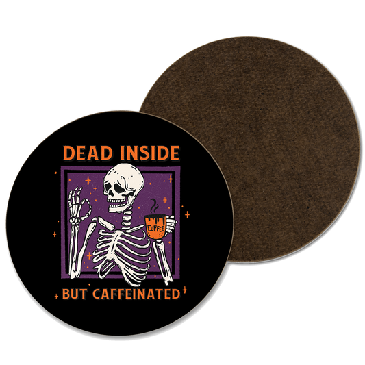 A black coaster with an illustration of a skeleton drinking coffee with the phrase ‘dead inside but caffeinated’ written