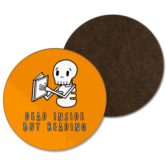 An orange coaster with ‘dead inside but reading’ written and a skeleton reading a book illustration 