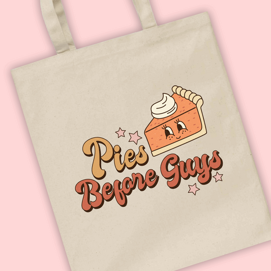 A natural tote bag with the phrase ‘pies before guys’ with an illustration of a pumpkin pie