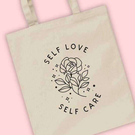 A natural tote bag with ‘Self love self care’ written with a rose flower illustration