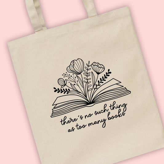 A natural tote bag with ‘There’s never too many books’ written with a book illustration with flowers
