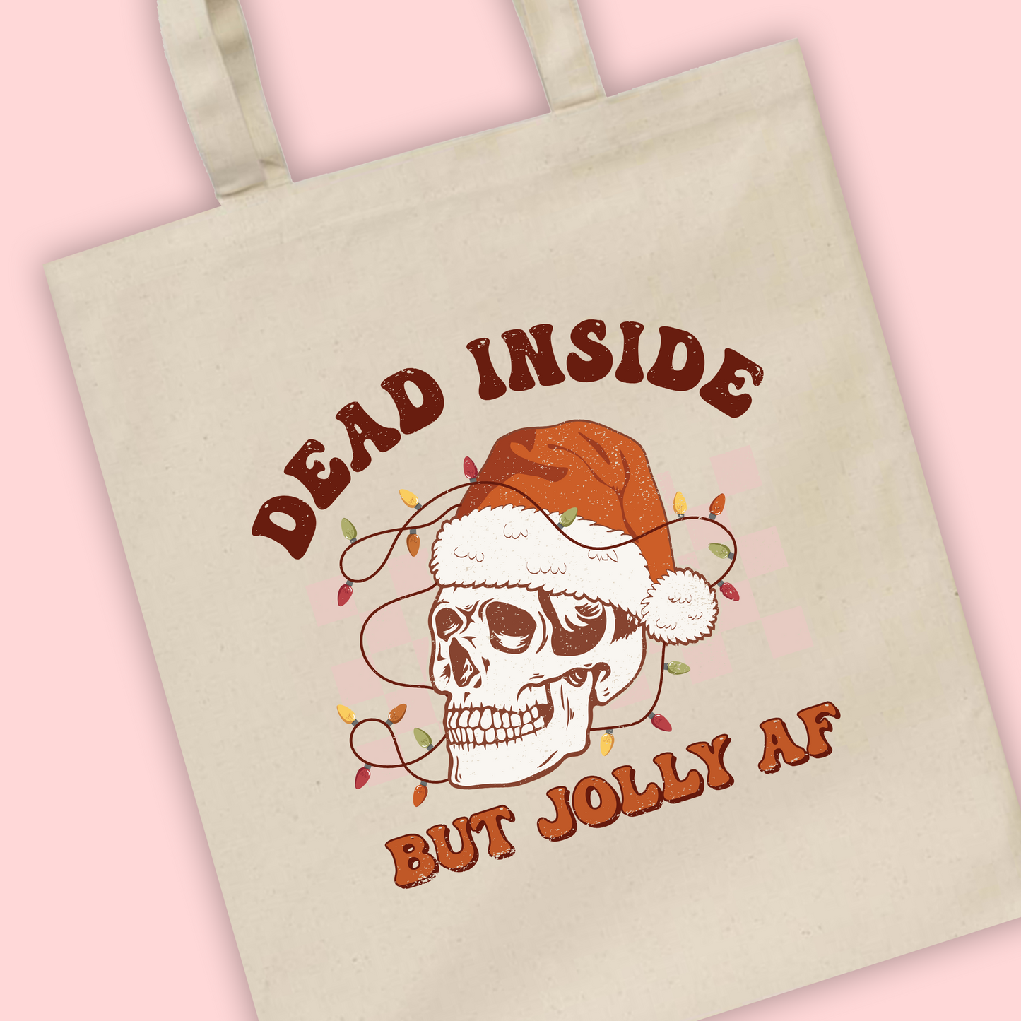 A natural tote bag with ‘Dead Inside but Jolly AF’ written with a Christmas Santa skeleton illustration 